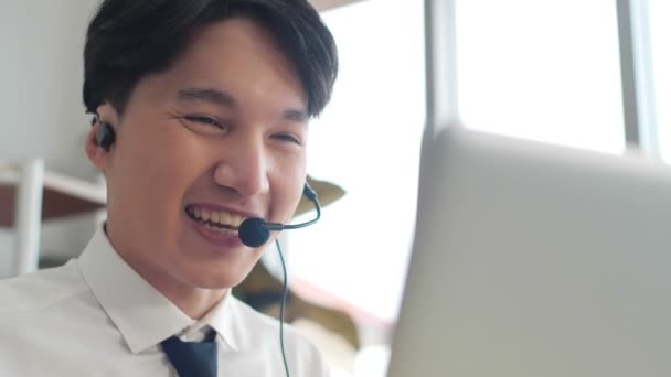 Asiático jovem homem de negócios usar fone de ouvido sem fio videoconferência chamando no computador portátil falar por webcam aprender ensinar no bate-papo on-line, webinar distância conceito de ensino online. Fechar - Filmagem, Vídeo
