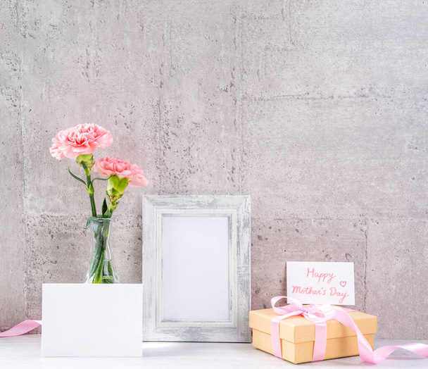 Zavřít, kopírovat prostor, vysmívat se, krásné matky denní koncept události ručně vyrobené dekorace GiftBox, kvetoucí čerstvé karafiáty s růžovou barevnou stuhou izolovanou na šedé tapetě - Fotografie, Obrázek