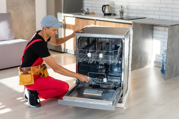 Майстер установки посудомийної машини в кухонному шафі
 - Фото, зображення