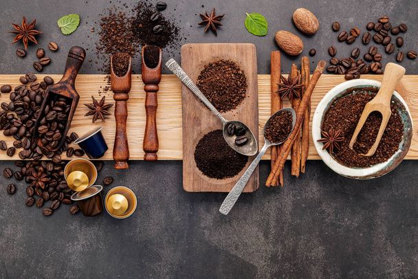 Geröstete Kaffeebohnen mit Kaffeepulver und geschmackvollen Zutaten für leckeren Kaffee auf dunklem Steinhintergrund. - Foto, Bild