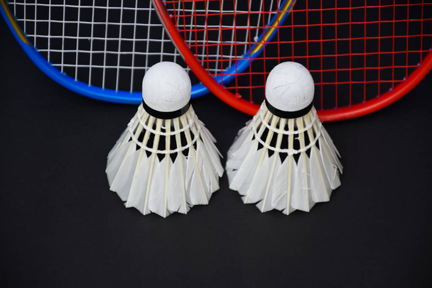 Beyaz badminton mekikleri ve raketler siyah zeminde, badminton kortunda fotokopi alanı, dünyanın her yerinde badminton severler için konsept. - Fotoğraf, Görsel