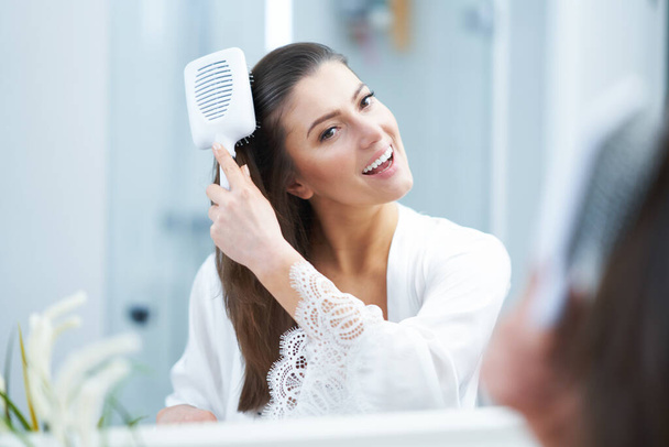 Junge schöne brünette Frau im Badezimmer Haarpflege - Foto, Bild