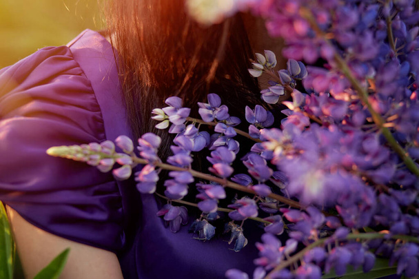 Kobieta trzyma fioletowe łubinki. Bliskość natury. Koncepcja samopoznania. Bardzo szeroki baner z przestrzenią do kopiowania. - Zdjęcie, obraz