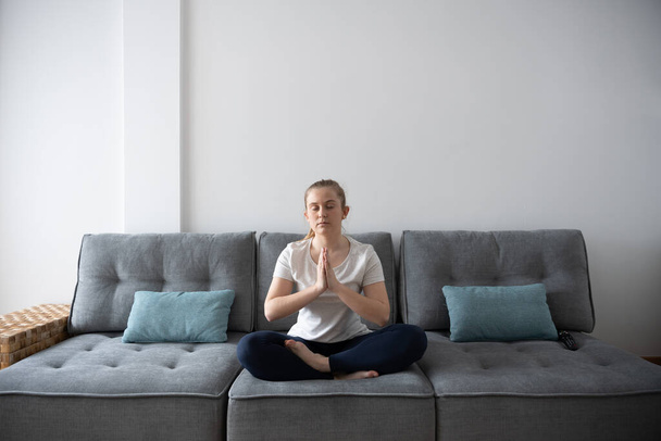 Молодая женщина медитирует на диване - Фото, изображение