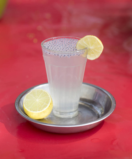 Verre d'eau de chaux ou de limonade sur un plateau en plastique rouge humide - Photo, image