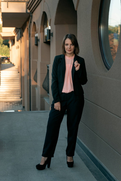Γυναίκα σκηνοθέτης με μαύρο κοστούμι και τακούνια. Επιχειρηματίας με σακάκι και παντελόνι. Επίσημα ενδύματα επιχειρήσεων - Φωτογραφία, εικόνα