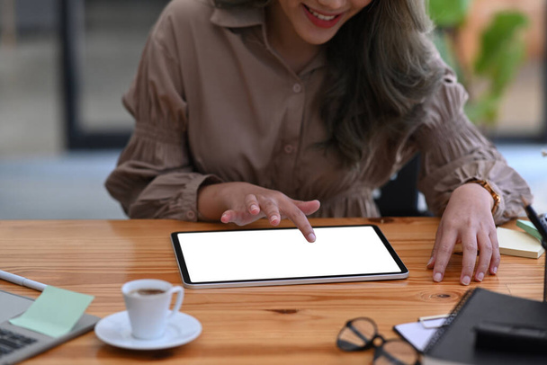 Cropped shot smiling female designer using digital tablet on wooden desk. - Valokuva, kuva