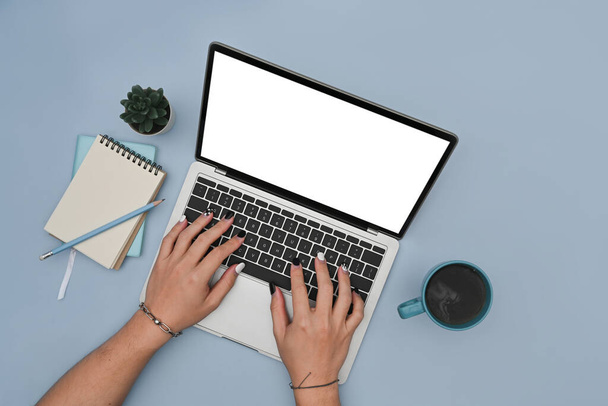 Vrouw handen typen op laptop computer over blauwe achtergrond. - Foto, afbeelding