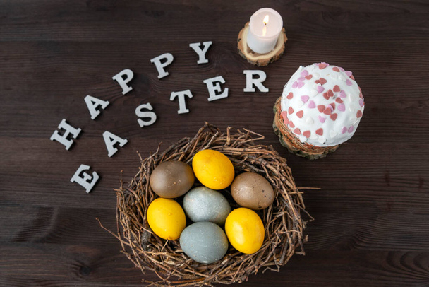 Happy easter flat lay. Easter eggs, kulich and candle on wooden background - Foto, imagen