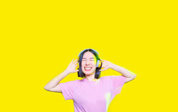 Młoda Azjatka słuchająca muzyki śmiejąca się w odosobnionym tle - przycięty sztandar - Zdjęcie, obraz