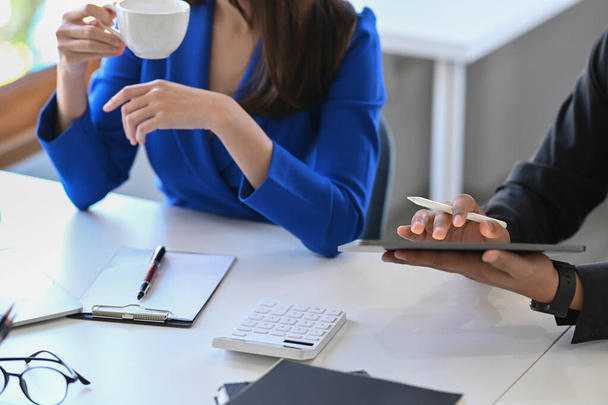 Обрезанная бизнесвумен держит чашку кофе и обсуждает стратегию проекта со своим коллегой в офисе. - Фото, изображение