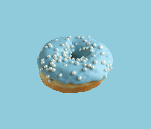 Donuts cobertos com gelo azul pálido e polvilhados com pérolas de açúcar em um fundo azul claro. Fechar. - Foto, Imagem