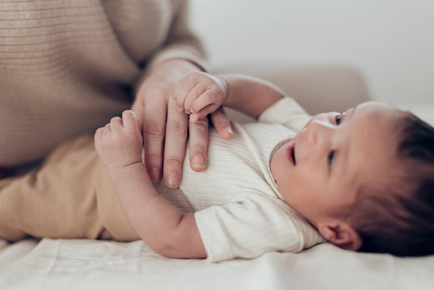 mano della mamma che accarezza la pancia del neonato sdraiato nel letto - Foto, immagini
