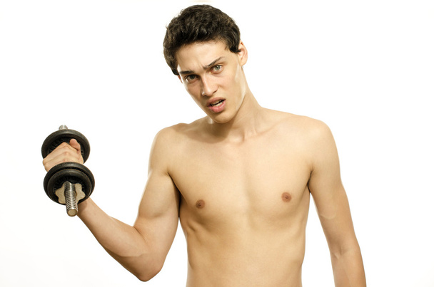Skinny man training his bicep muscle. Beautiful teenager lifting a dumbbell.Anorexic young man training to become stronger - Photo, Image