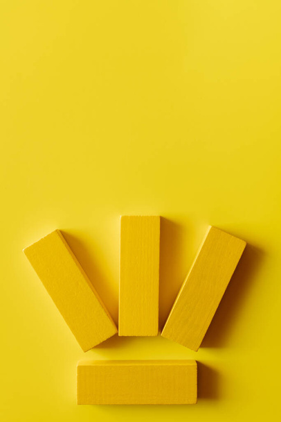 bovenaanzicht van vier gekleurde blokken op gele achtergrond - Foto, afbeelding
