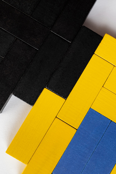primer plano de bloques azules, negros y amarillos sobre fondo blanco, vista superior - Foto, Imagen