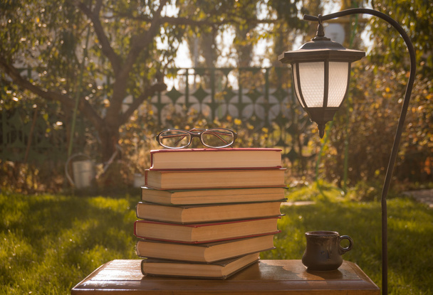 Uma pilha de livros e uma lanterna de jardim
 - Foto, Imagem
