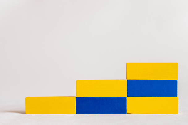 trap gemaakt van rechthoekige blauwe en gele blokken op witte achtergrond, Oekraïense concept - Foto, afbeelding