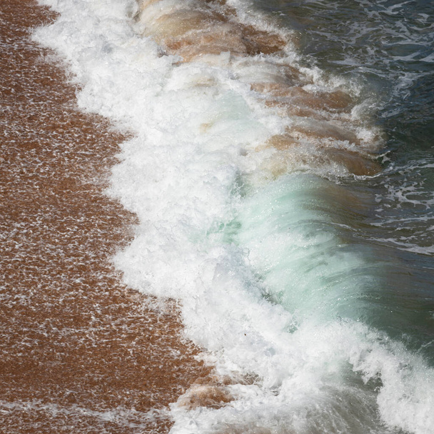 a wave from ocean crashing onto sand at the beach  - Photo, Image
