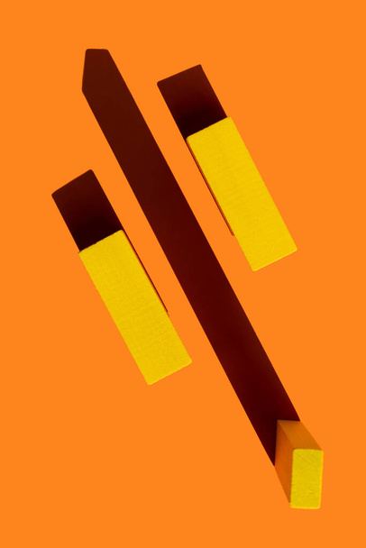 top view of yellow quadrangular blocks on bright orange background with shadows - Photo, image