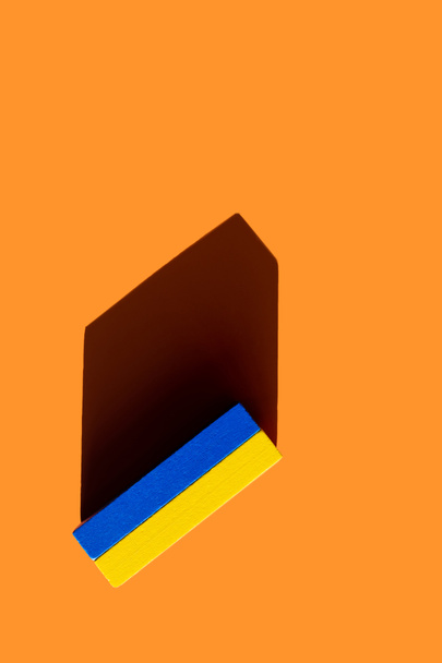 top view of bright blue and yellow blocks on orange background, ukrainian concept - Photo, Image