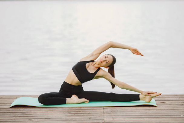 Woman practicing advanced yoga by the water - Foto, imagen