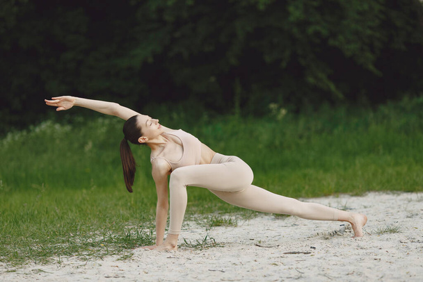 Woman practicing advanced yoga in a beach - Foto, Imagem
