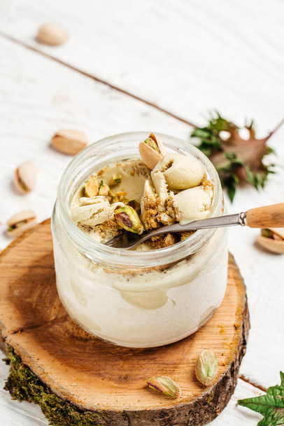Homemade pistachio ice cream in a glass jar fresh pistachio over white background. vertical image. top view. place for text, - 写真・画像