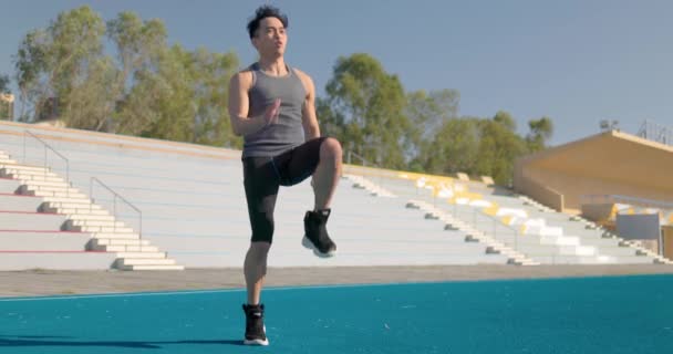 Строгий атлетичный человек энергично бегает на месте на открытом воздухе стадиона - Кадры, видео