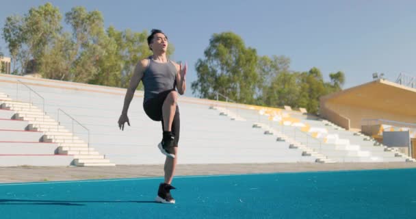 Strong Athletic Fit Man jest energicznie jogging w miejscu na stadionie na świeżym powietrzu - Materiał filmowy, wideo