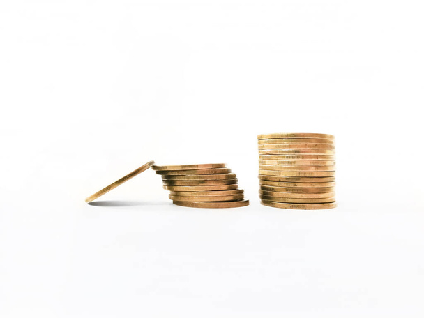 Zwei Stapel Münzen auf weißem Hintergrund. Ein Ponette ruht auf einem Stapel. Euro und Dollar, Wechselkurs. - Foto, Bild