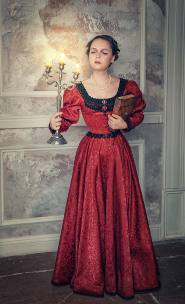 Красива жінка в середньовічній сукні з канделябрам
 - Фото, зображення