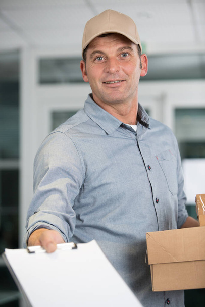 delivery man with clipboard on light background - Foto, afbeelding