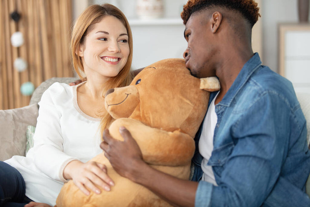 happy young man is giving teddy bear to woman - Foto, afbeelding