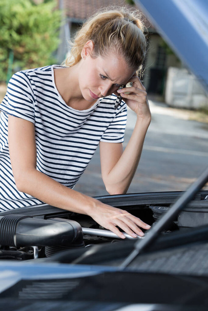 woman on the phone next to broken car engine - Foto, imagen