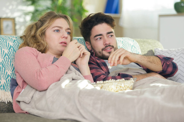 emotional couple snuggled under a blanket watching a movie - Valokuva, kuva