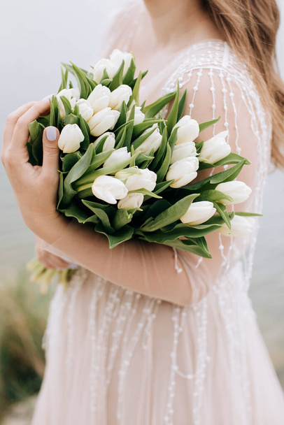 Beautiful large bouquet of white tulips in the hands of the bride - 写真・画像