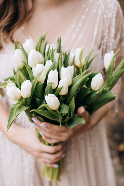 Many white tulips in the hands of the bride. A wonderful gift - Photo, Image