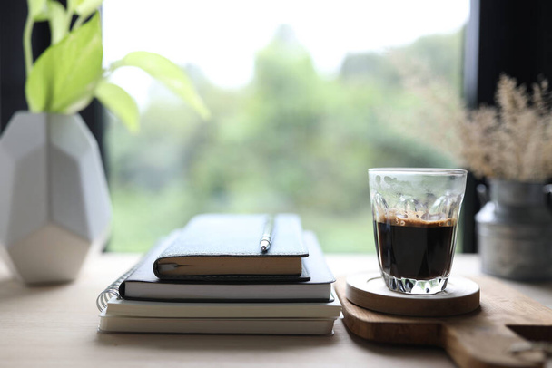 Dagboek notitieboekje en koffiekopje in op houten tafel met raamzicht - Foto, afbeelding