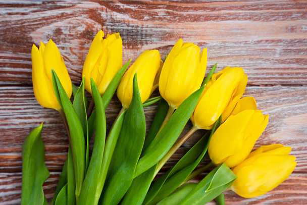 Krásné žluté tulipány na dřevěném pozadí. Den matek, 8. března, Valentýn, narozeninová oslava. Banner. Horní pohled. Selektivní zaměření. - Fotografie, Obrázek