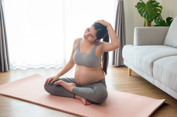 Young pregnant woman doing yoga at home, healthcare and pregnancy care concept - Fotó, kép