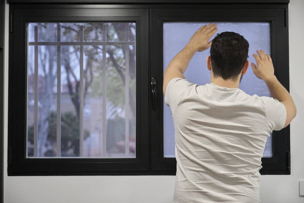 Muž instaluje matné okno vinyl na mokré okno sklo. - Fotografie, Obrázek