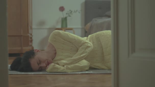 Młoda kobieta leżąca w mieszkaniu na podłodze i cierpiąca z powodu bólu kłutego - Materiał filmowy, wideo