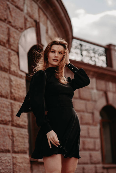 Beautiful girl in a black dress on the street - Fotoğraf, Görsel