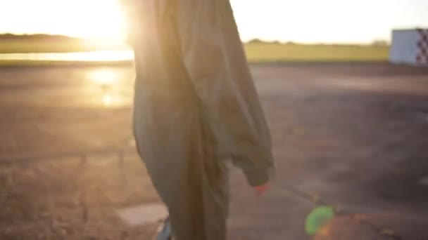 Pilot wojskowy spacerujący w bazie o zachodzie słońca. Niski kąt widzenia.  - Materiał filmowy, wideo