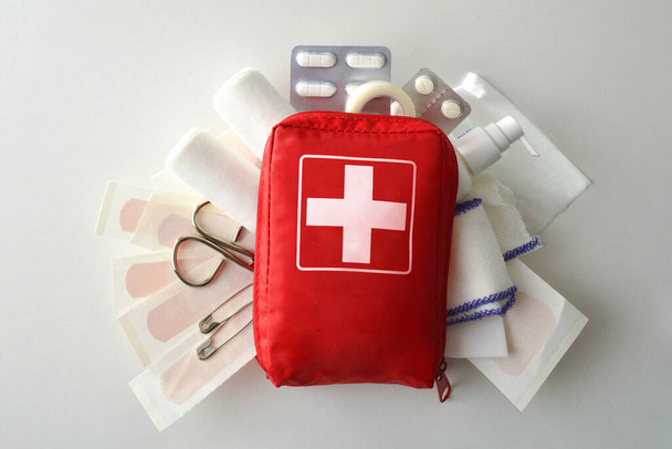 Travel portable first aid bag full of objects and tools for minor cures on white table. Top view. Horizontal composition - Foto, afbeelding