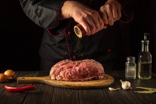 Lo chef prepara carne di vitello cruda. Prima della cottura, lo chef aggiunge pepe al manzo. Piatto nazionale è in preparazione in cucina. - Foto, immagini