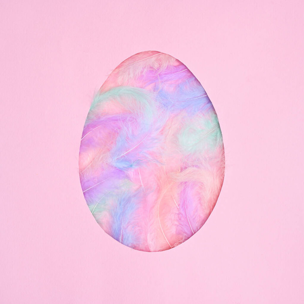 Egg shape frame with natural colorful feathers on pastel pink background. Flat lay creative Easter concept - Fotografie, Obrázek