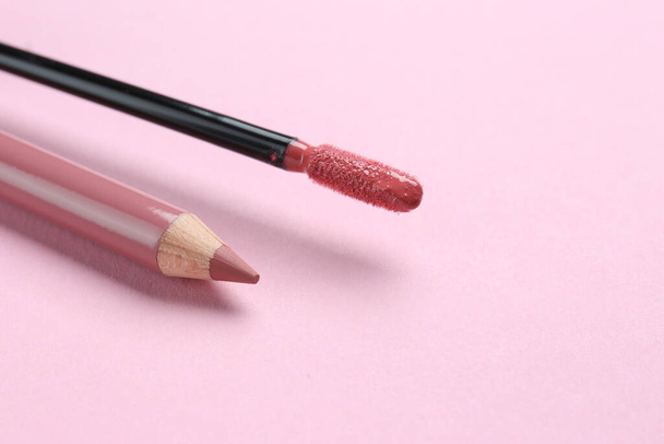 Lip pencil and brush of liquid lipstick on pink background, space for text. Cosmetic products - Foto, immagini