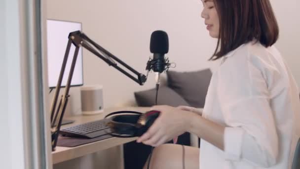 Gyönyörű fiatal ázsiai nő podcaster beszél egy mikrofonba, miközben rögzíti a podcast és élő streaming tartalmat a közösségi média. - Felvétel, videó